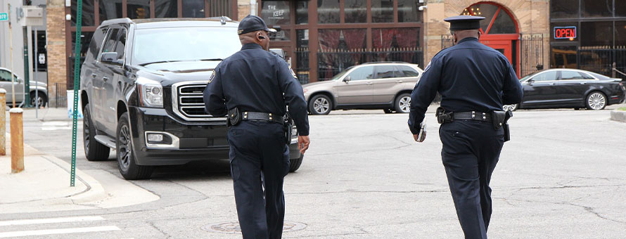 Two police officers in uniform walking on the street.